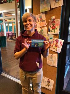 Elmo's Diner employee smiling at the camera and holding the "breastfeeding welcome here" sign