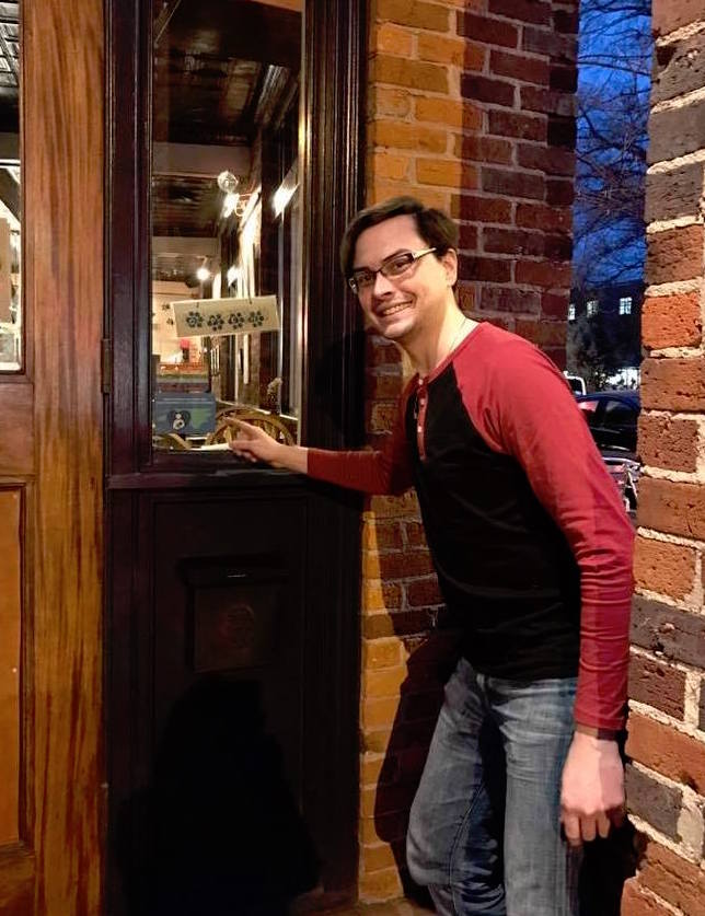 Spotted Dog Restaurant employee pointing to breastfeeding welcome here sign on window next to front door