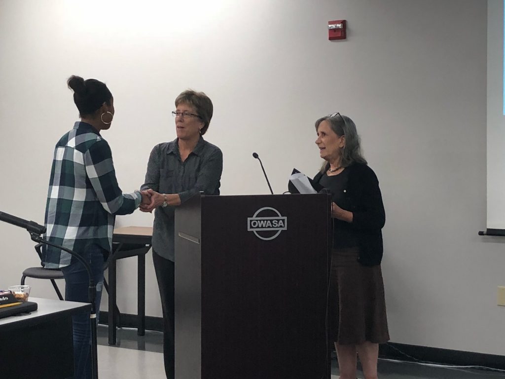 Carrboro Mayor is smiling and shaking hands with a breastfeeding family friendly communities supporter while another support holds the proclamation and looks on.