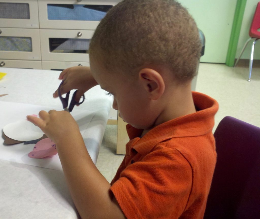 Child cutting paper with scissors.